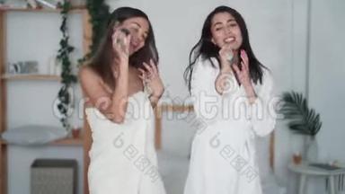 两个穿着白色浴袍跳舞的女人姐姐在卧室里唱歌和笑，搞笑视频